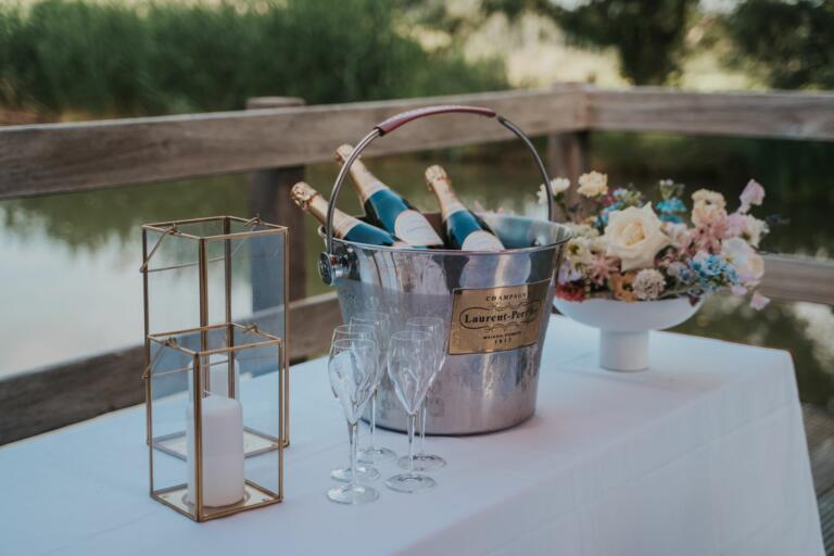 Feiern & Hochzeiten im Hofgut Georgenthal. Sektflaschen auf feierlichem Tisch am Wasser.