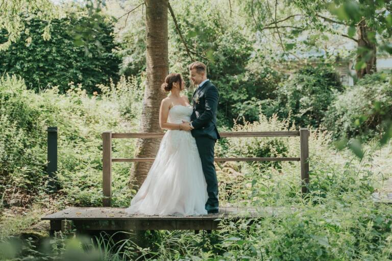 Romantische Hochzeit im Hofgut Georgenthal: Ein Brautpaar am idyllischen Weiher, umgeben von der grünen Natur des Taunus.
