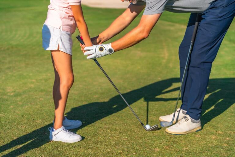 Ein Lehrer zeigt einem Golfschüler auf einem Golfplatz des Hofguts Georgenthal, wie man einen Golfschläger hält und schwingt.