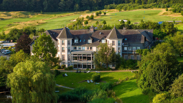Blick auf das Hofgut Georgenthal mit Hotel, Golfplatz und der umliegenden grünen Landschaft des Taunus.